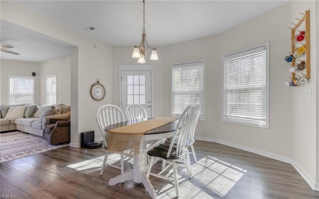 dining area featuring wood finished floors, visible vents, a chandelier, and baseboards