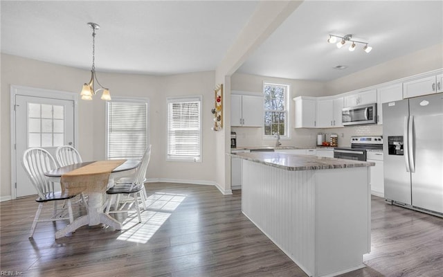 kitchen with a kitchen island, dark wood finished floors, white cabinetry, stainless steel appliances, and decorative backsplash