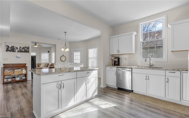 kitchen featuring dishwasher, decorative backsplash, light stone countertops, and a center island