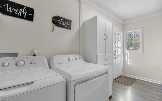 laundry room with wood finished floors, baseboards, laundry area, a textured wall, and washer and clothes dryer