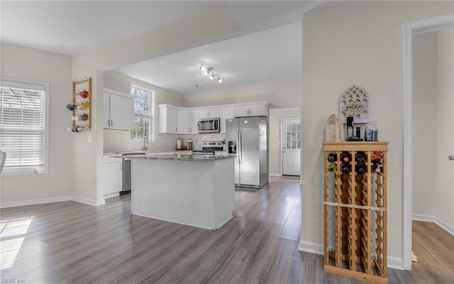 kitchen featuring tasteful backsplash, wood finished floors, a center island, appliances with stainless steel finishes, and white cabinets