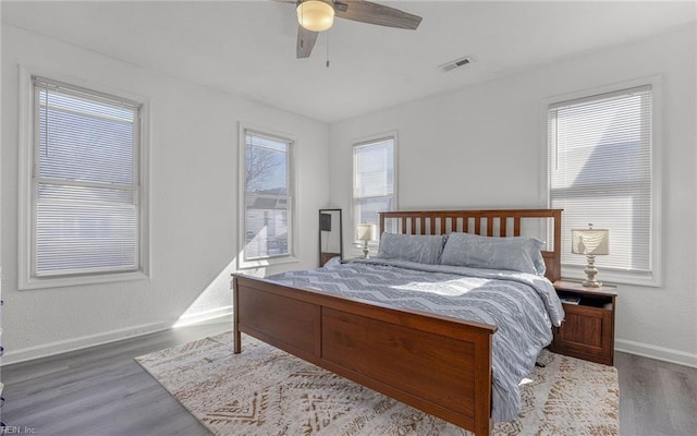 bedroom featuring visible vents, multiple windows, baseboards, and wood finished floors