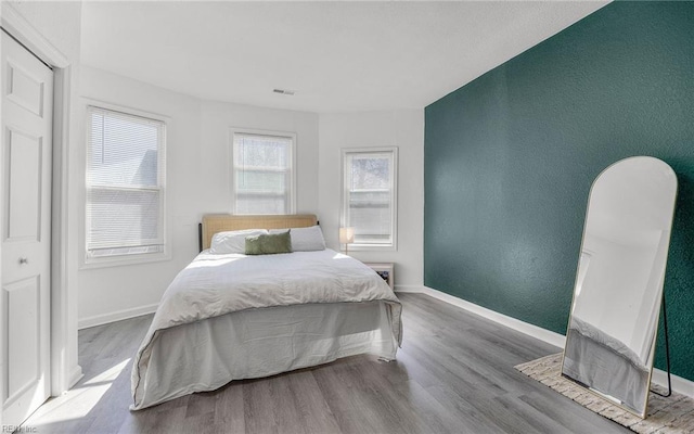 bedroom with visible vents, baseboards, and wood finished floors