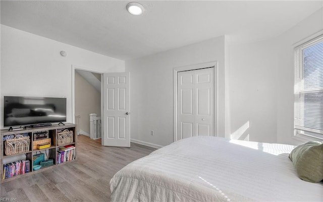 bedroom featuring a closet, baseboards, and wood finished floors