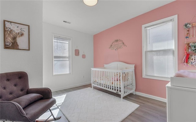 bedroom with visible vents, wood finished floors, and baseboards