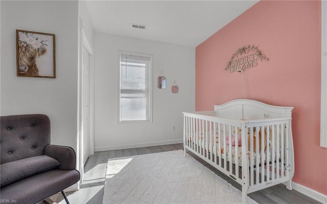 bedroom with visible vents, baseboards, and wood finished floors