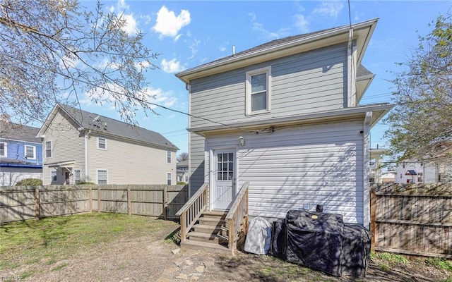 back of house with entry steps, a yard, and fence