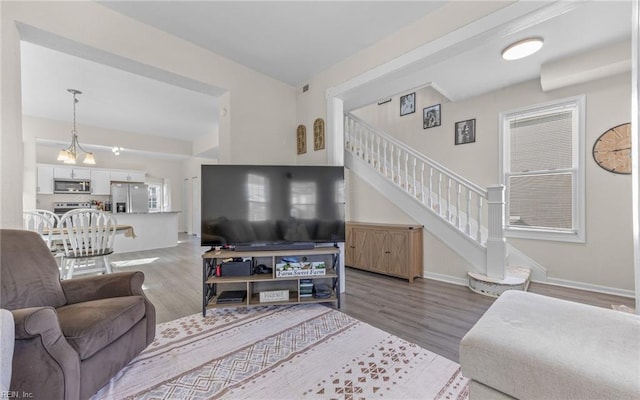 living area with stairway, baseboards, and wood finished floors