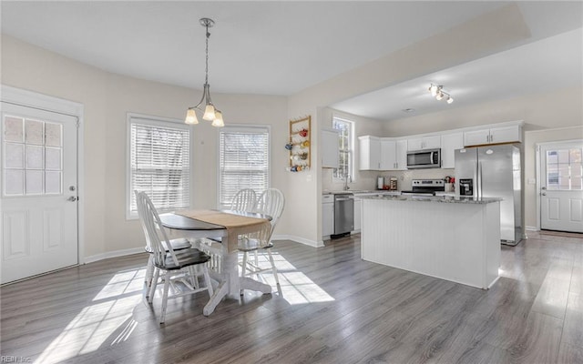 dining space featuring baseboards, a notable chandelier, and wood finished floors