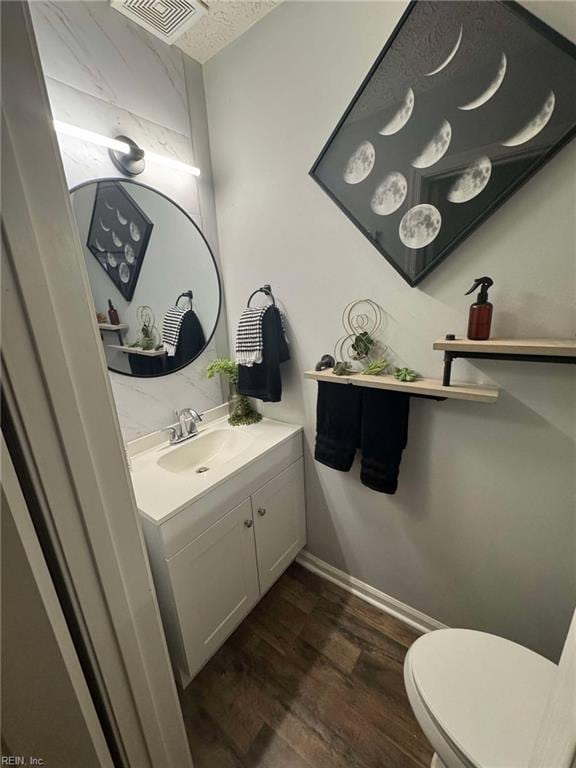 bathroom featuring vanity, wood finished floors, visible vents, baseboards, and toilet