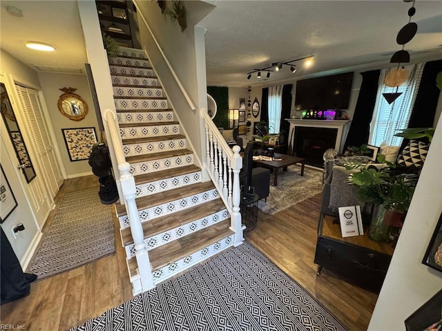 stairs featuring a fireplace, track lighting, and wood finished floors