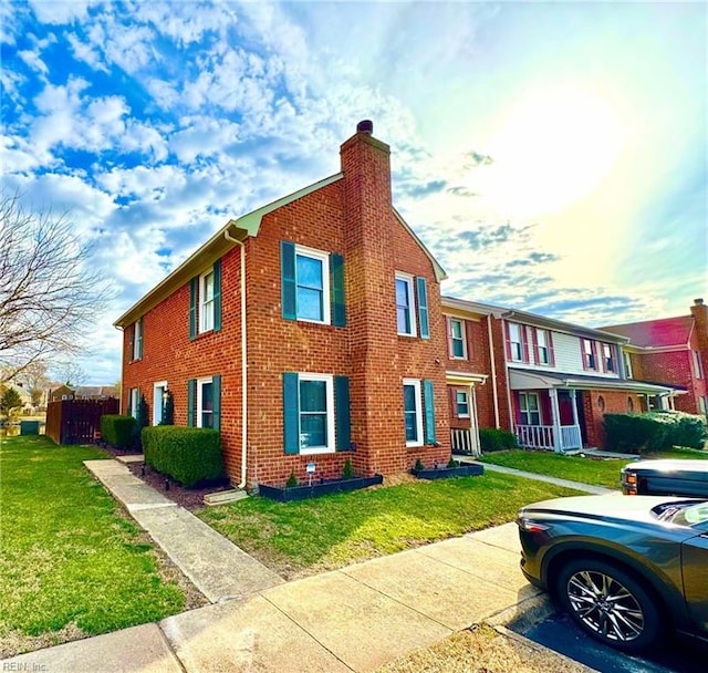 view of front of house featuring a front yard, fence, brick siding, and a chimney