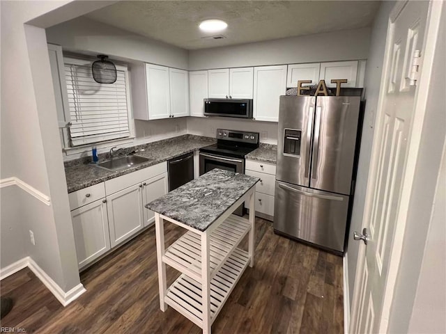 kitchen with white cabinets, appliances with stainless steel finishes, dark wood-type flooring, and a sink