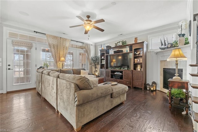 living area with a glass covered fireplace, dark wood-type flooring, and ornamental molding