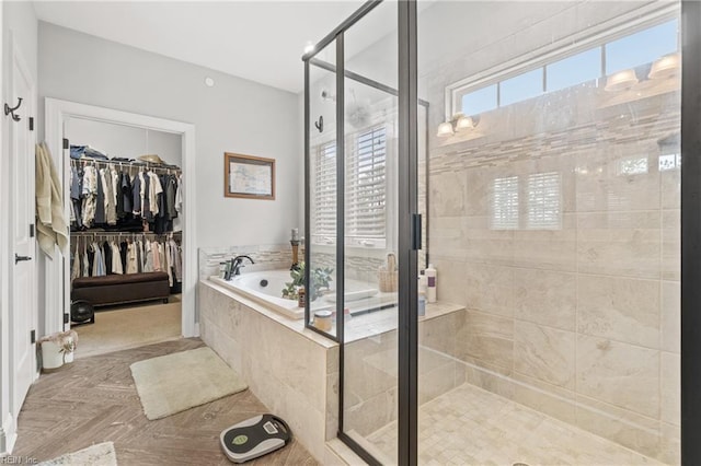 bathroom with a walk in closet, a garden tub, and a stall shower