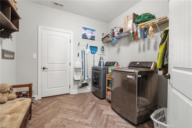 washroom with visible vents, baseboards, laundry area, and washing machine and clothes dryer