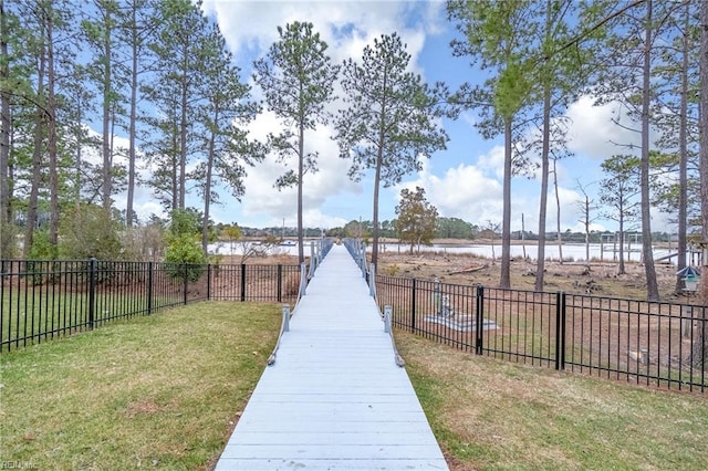 view of home's community with a lawn, a water view, and fence