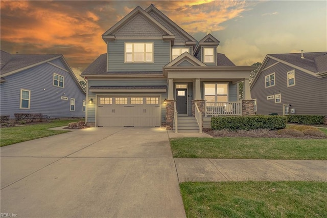 craftsman-style home featuring a garage, a front lawn, covered porch, and driveway