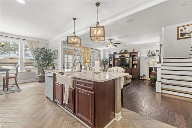 kitchen with a kitchen island with sink, a sink, light countertops, dishwasher, and crown molding