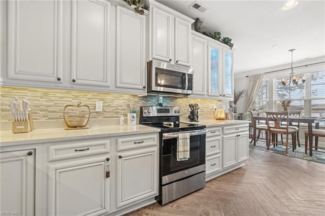 kitchen with visible vents, decorative light fixtures, white cabinetry, stainless steel appliances, and decorative backsplash