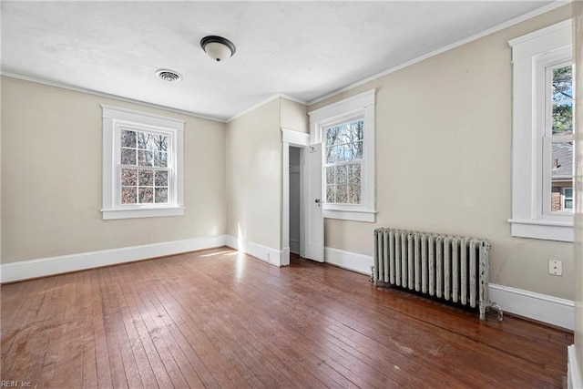 unfurnished bedroom featuring baseboards, wood-type flooring, radiator heating unit, and ornamental molding