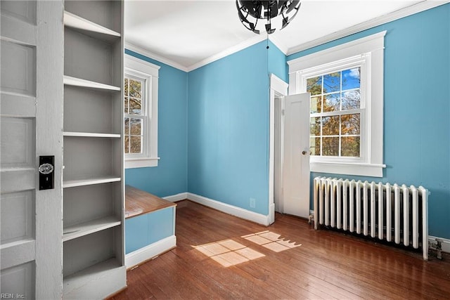 interior space featuring crown molding, radiator heating unit, baseboards, and wood-type flooring