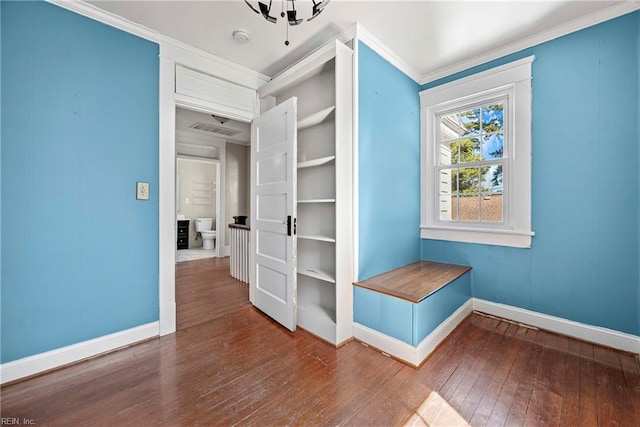 interior space with visible vents, wood-type flooring, baseboards, and crown molding