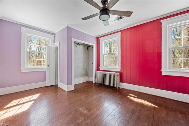 unfurnished bedroom with baseboards, visible vents, radiator heating unit, ornamental molding, and hardwood / wood-style flooring