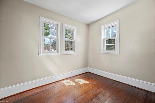 spare room with a wealth of natural light, baseboards, and hardwood / wood-style floors