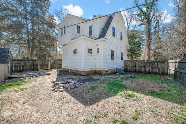 rear view of house featuring central air condition unit, a gambrel roof, an outdoor fire pit, a fenced backyard, and crawl space