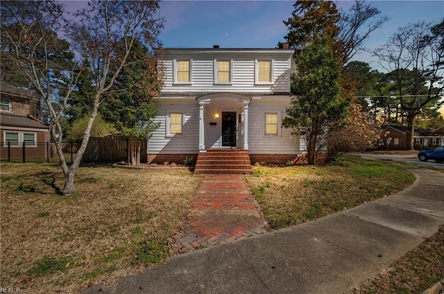 traditional home with a front lawn and fence