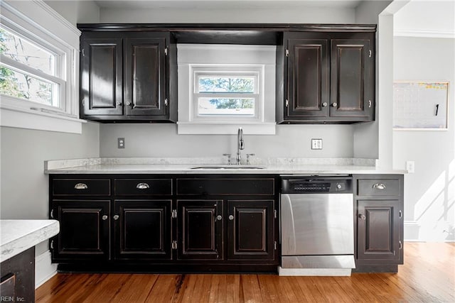 kitchen featuring a sink, wood finished floors, light countertops, and stainless steel dishwasher