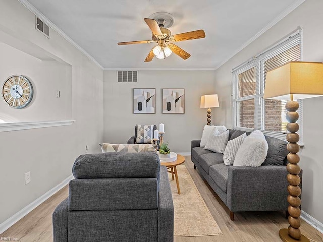 living room with a ceiling fan, baseboards, visible vents, light wood finished floors, and ornamental molding