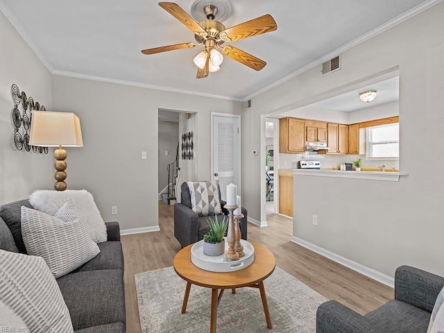 living room with crown molding, baseboards, visible vents, and light wood-type flooring