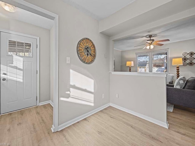 foyer entrance with light wood-style flooring, a ceiling fan, and baseboards