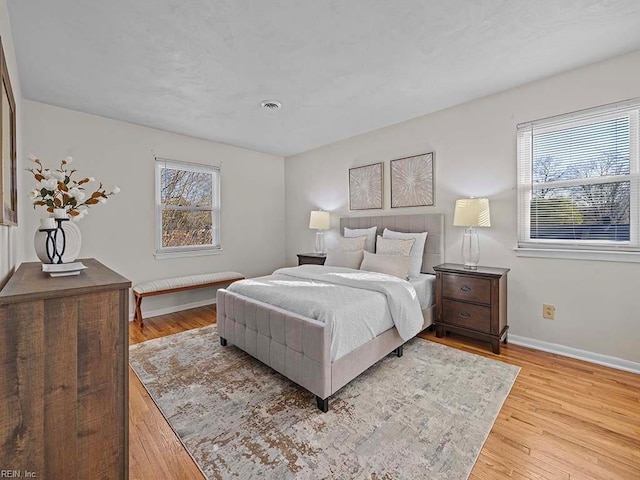 bedroom with multiple windows, baseboards, and wood finished floors