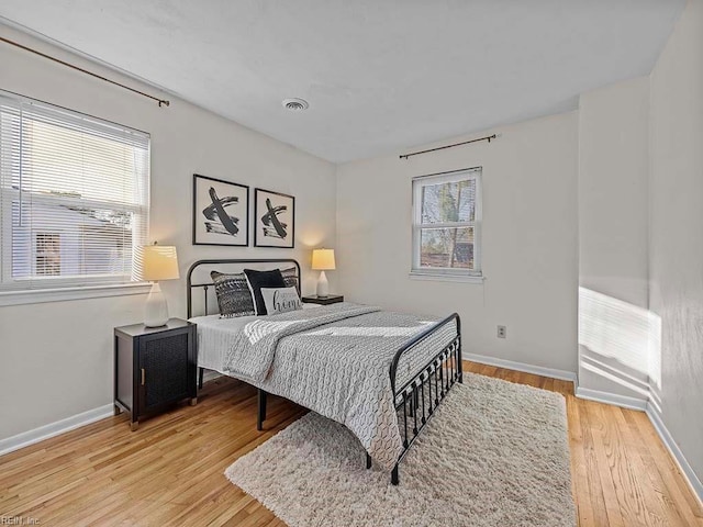 bedroom with light wood-style flooring, visible vents, and baseboards