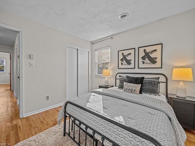 bedroom featuring visible vents, a closet, light wood-style floors, radiator, and baseboards