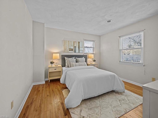 bedroom featuring visible vents, baseboards, and wood finished floors