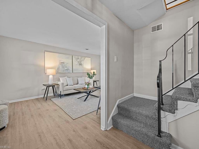 entrance foyer with stairway, wood finished floors, visible vents, and baseboards