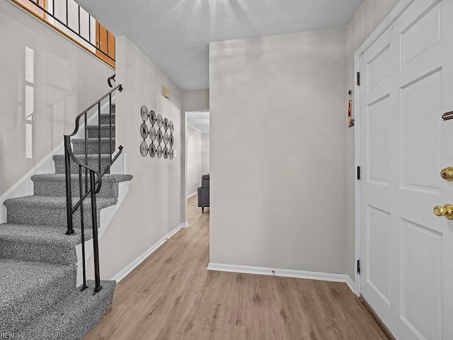 entrance foyer featuring light wood finished floors, stairway, and baseboards