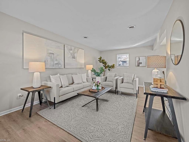 living area featuring light wood-style floors, visible vents, and baseboards