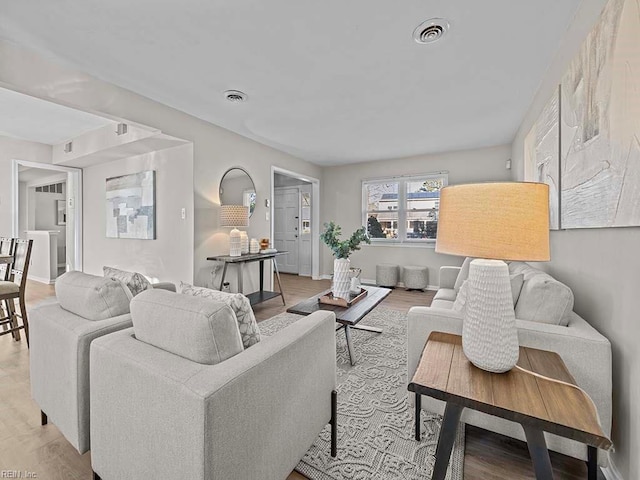 living area featuring baseboards, visible vents, and light wood finished floors