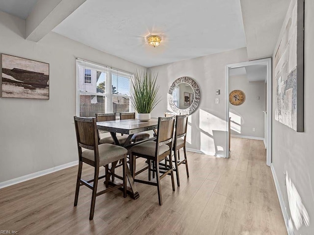 dining space featuring baseboards and light wood-style flooring