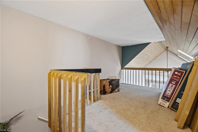 corridor featuring a textured ceiling, lofted ceiling, and carpet floors