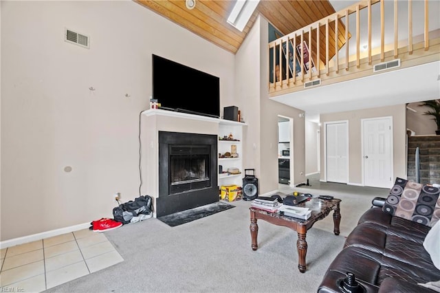 carpeted living room with visible vents, a fireplace with flush hearth, baseboards, and wooden ceiling