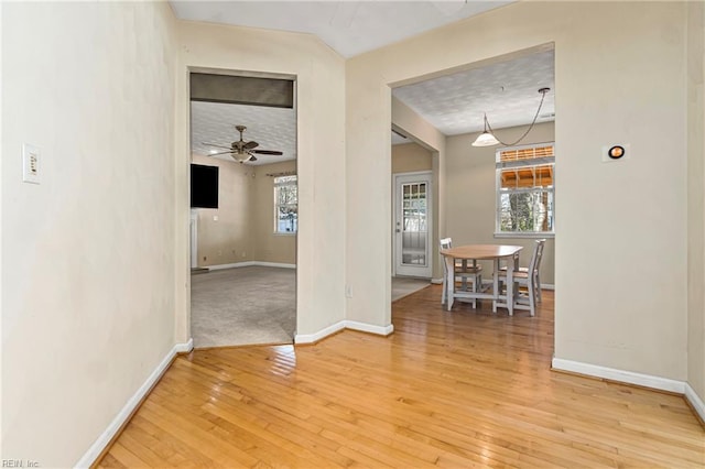 empty room featuring a healthy amount of sunlight, baseboards, and light wood finished floors