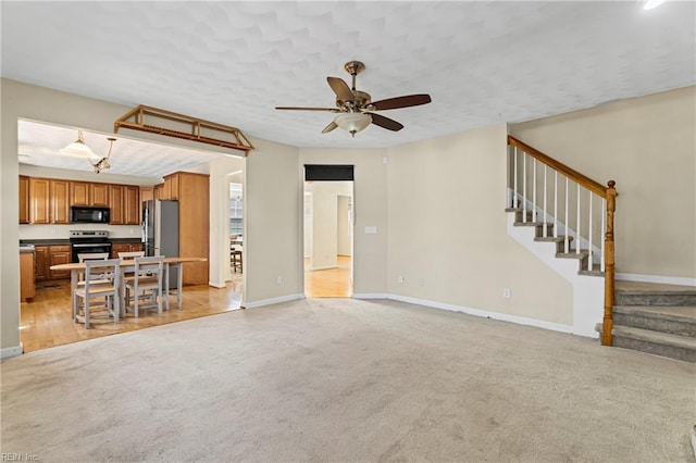 unfurnished living room with light carpet, a textured ceiling, stairs, and baseboards