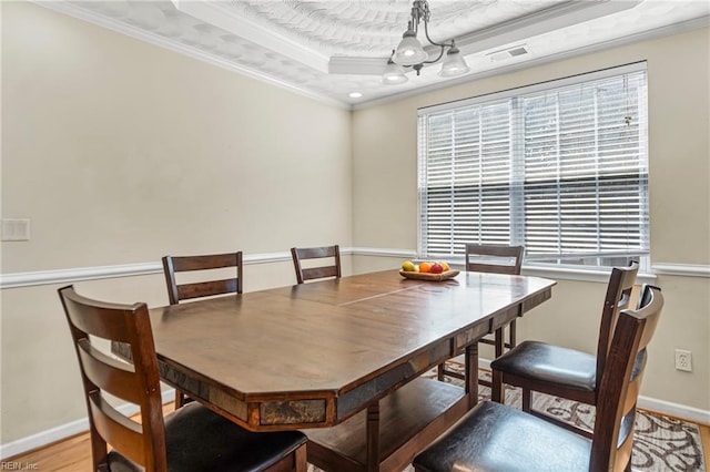 dining space featuring visible vents, a raised ceiling, baseboards, and crown molding