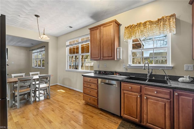 kitchen with light wood-style flooring, a sink, hanging light fixtures, dishwasher, and brown cabinets